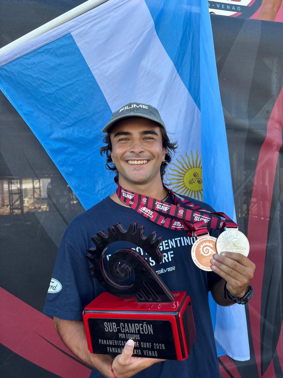 Santino con la bandera argentina, una medalla y un trofeo